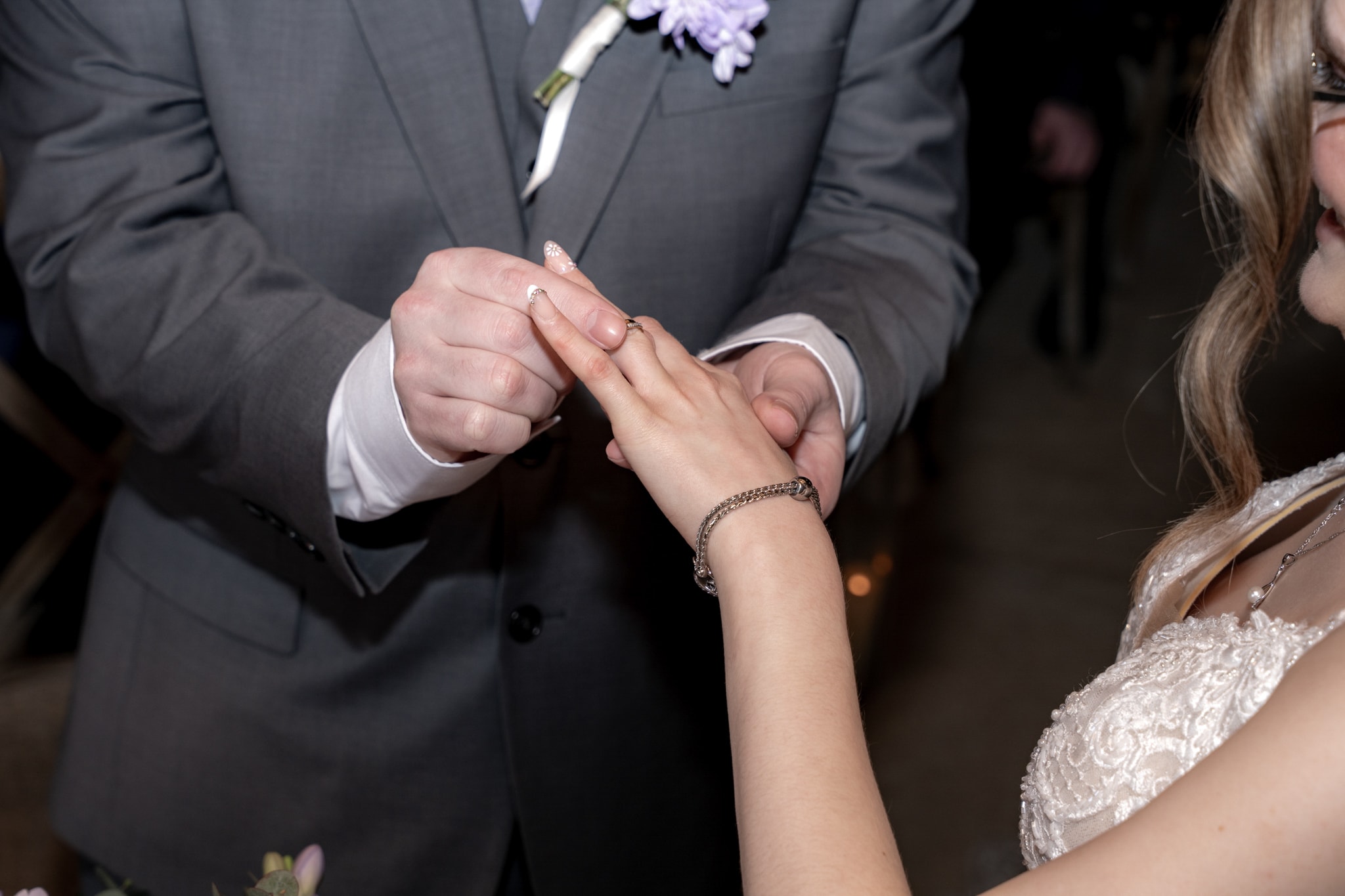 Groom placing wedding ring on bride's finger at Notley Tythe Barn