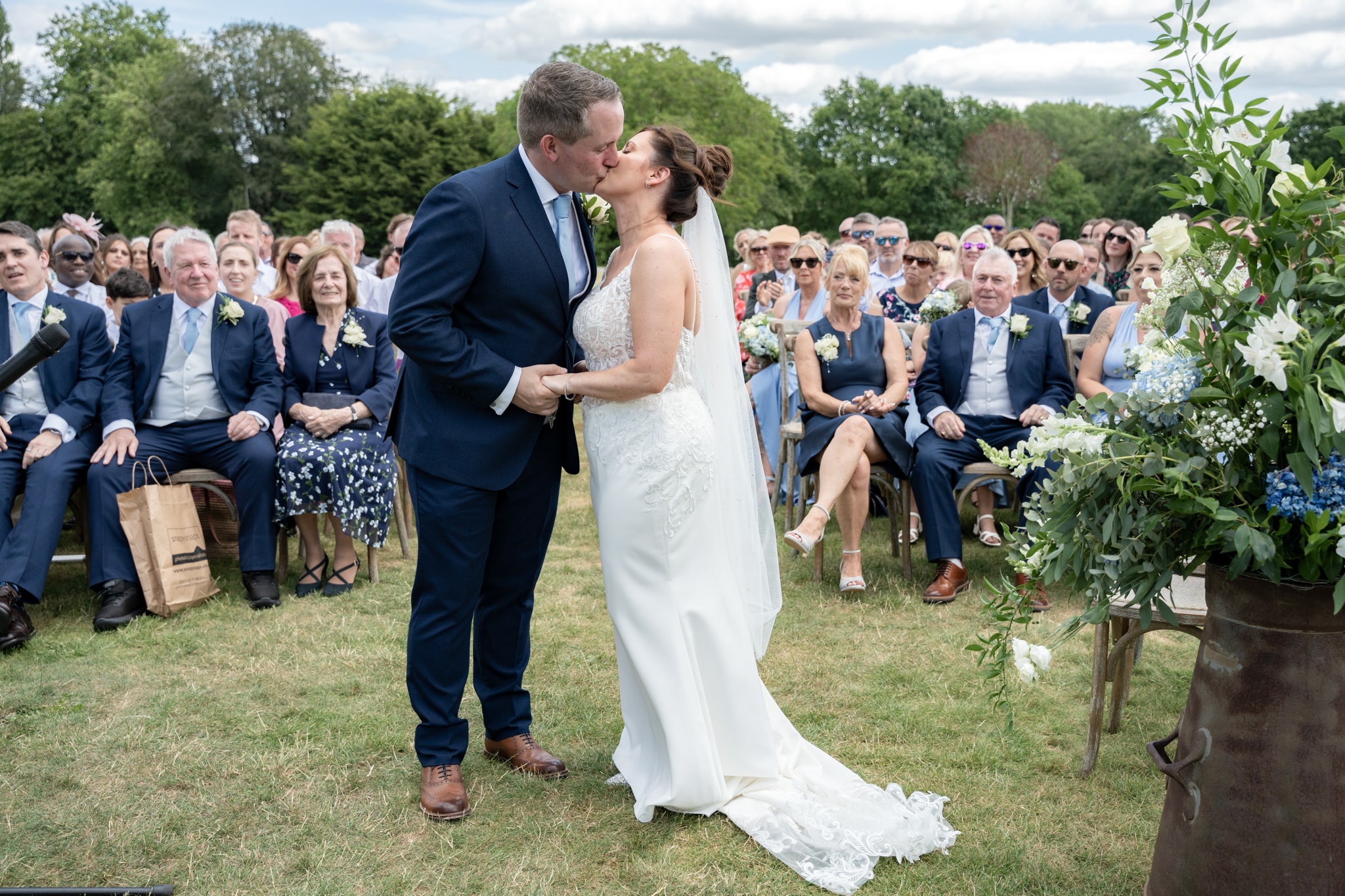 Bride and groom first kiss at outdoor Notley Tythe Barn ceremony