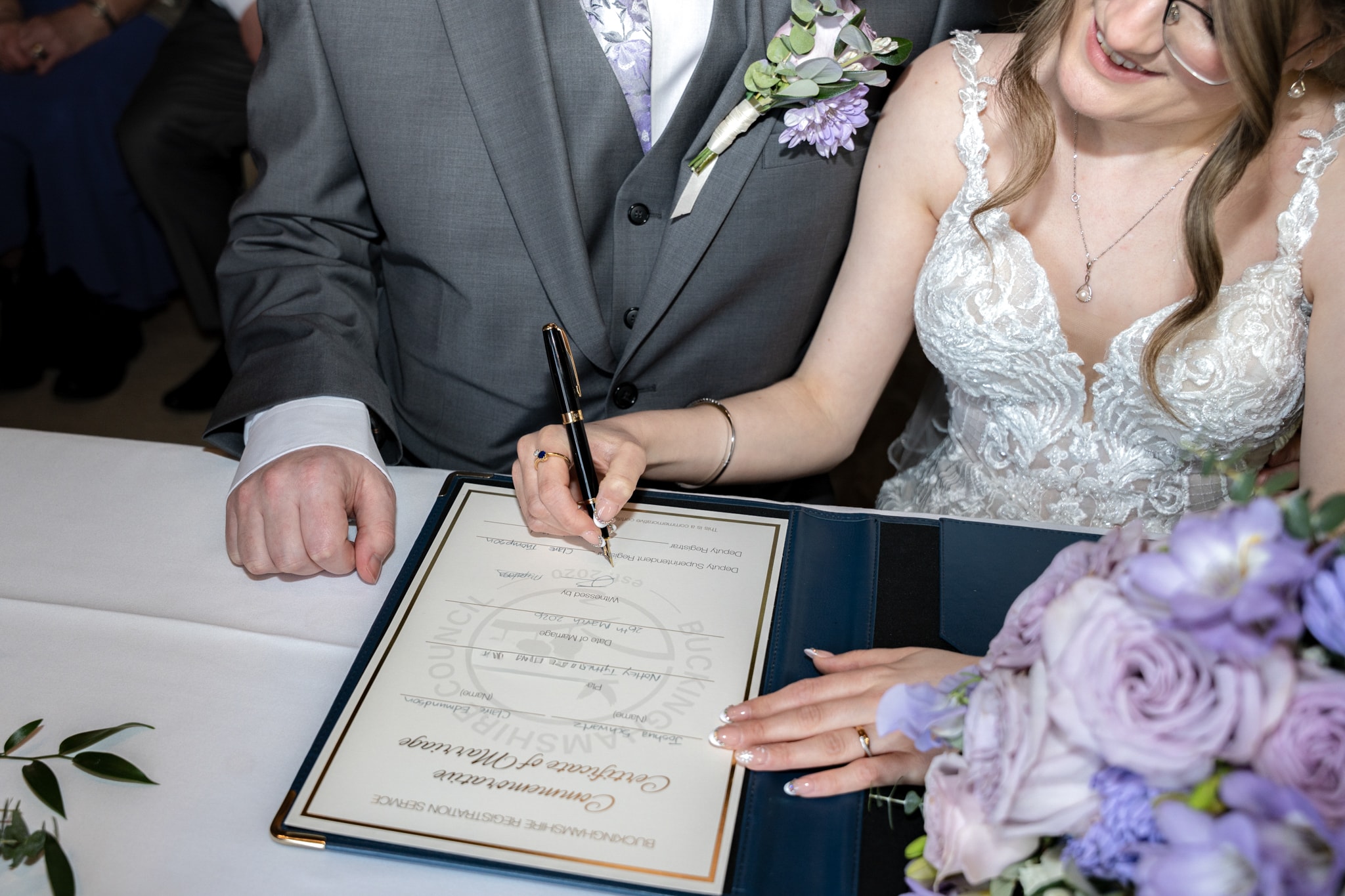 Close-up of bride signing the marriage certificate at Notley Tythe Barn