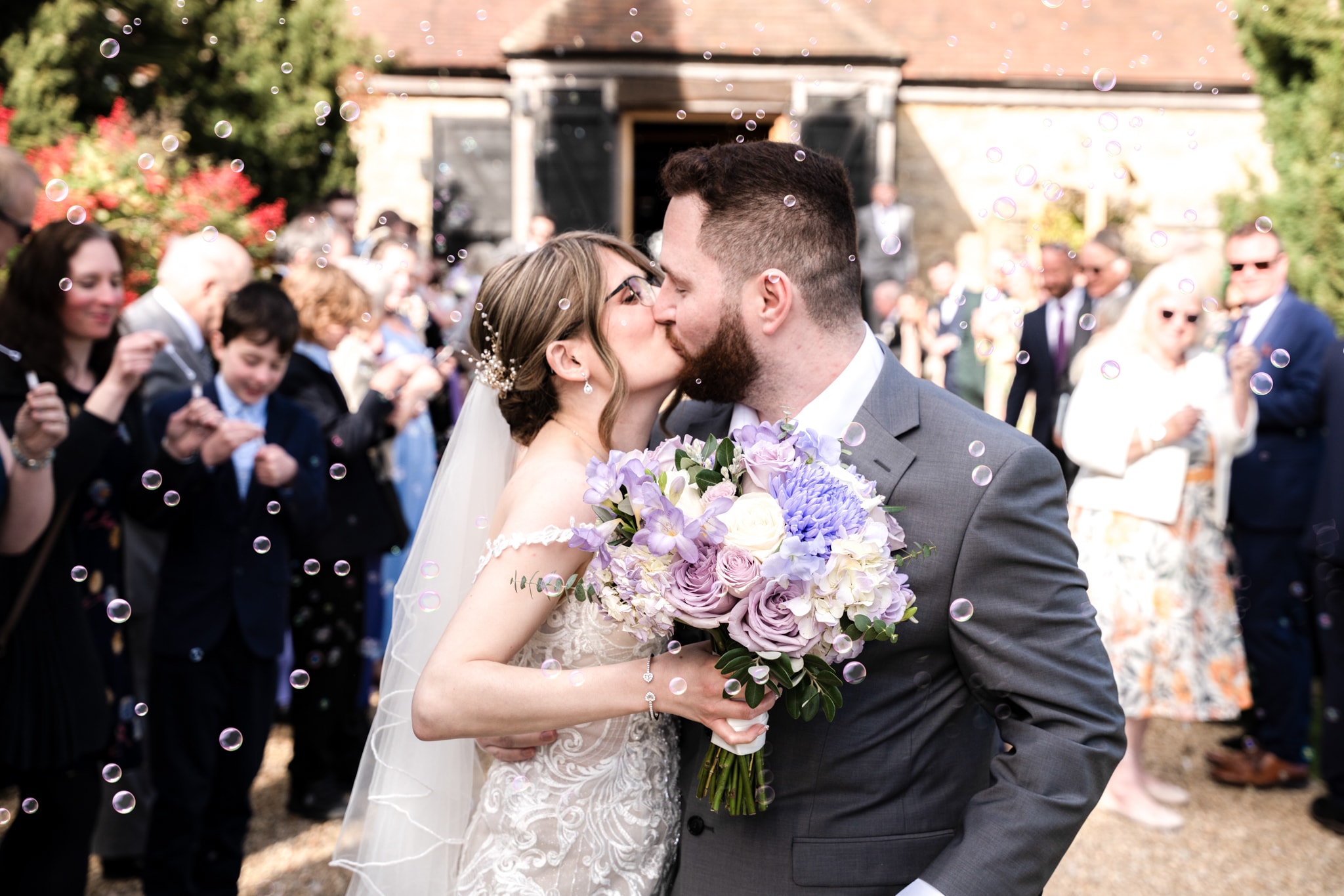 Bride and groom kissing during bubble exit at Notley Tythe Barn