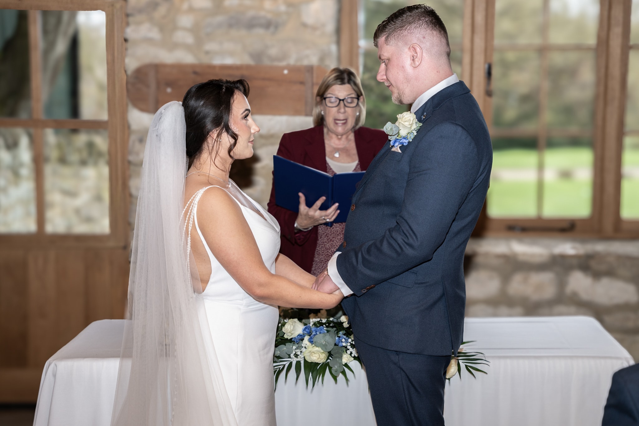 Bride and groom exchanging vows at the altar inside Notley Tythe Barn ceremony room