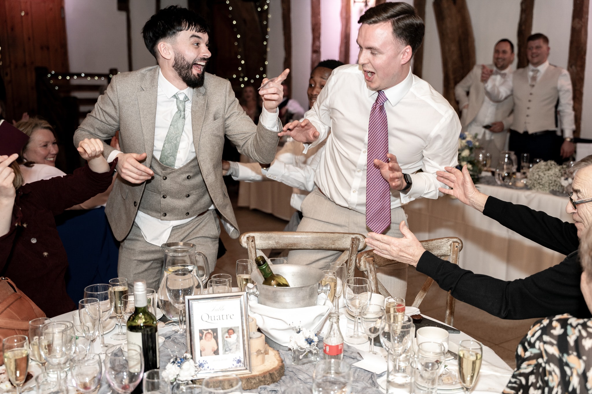 Two groomsmen dancing and celebrating at wedding reception inside Notley Tythe Barn