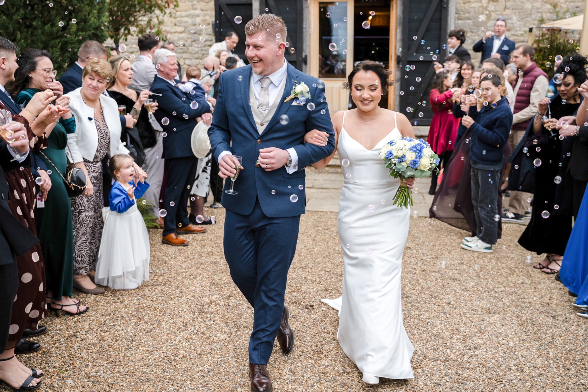 Bride and groom walking through bubble-filled exit at Notley Tythe Barn